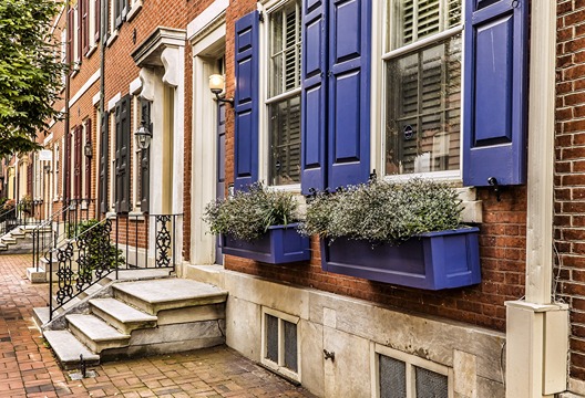A view of several doorfronts of brick homes along Elfreth's Alley