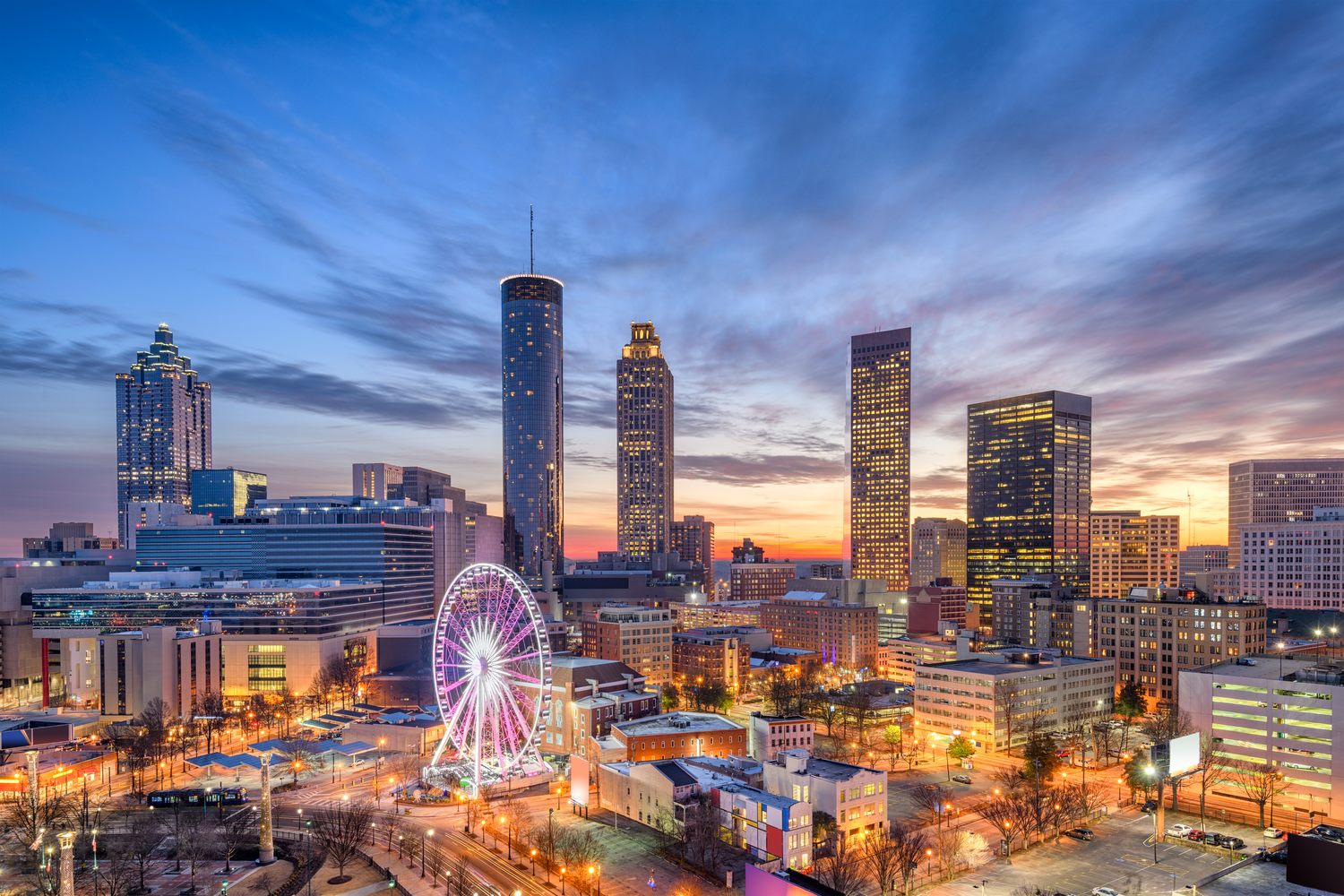 The downtown Atlanta skyline at dusk with the SkyView ferris wheel lit up over Centennial Olympic Park