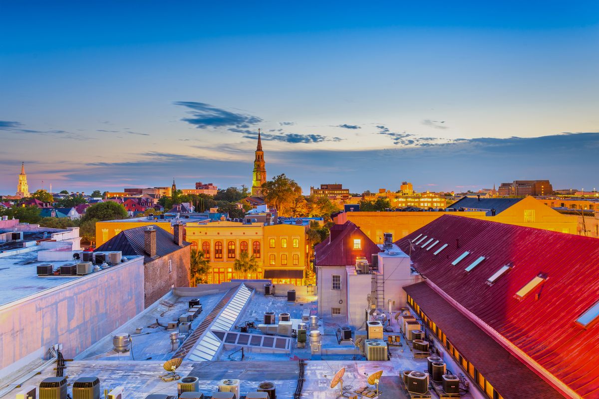 Charleston rooftops at dusk, the red roof of the City Market in front and St. Michael’s steeple on the skyline