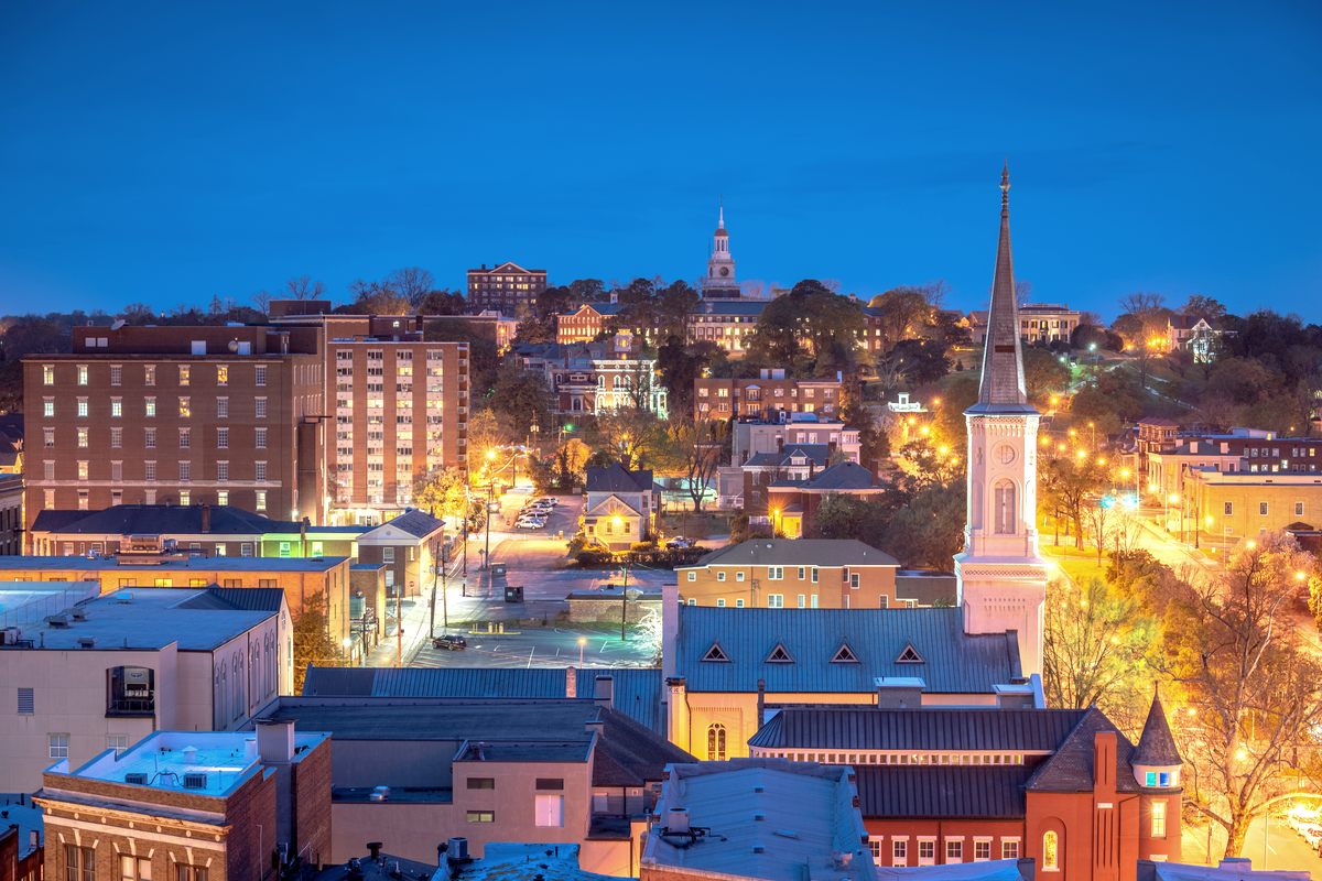 Downtown Macon at dusk, church steeples and warm-lit streets under a deep blue sky