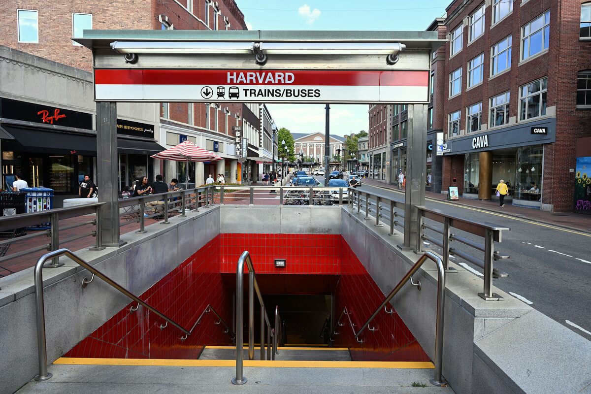 The red-tiled stairs down into Harvard station on Brattle Street in Harvard Square, under a canopy sign reading Harvard, Trains/Buses