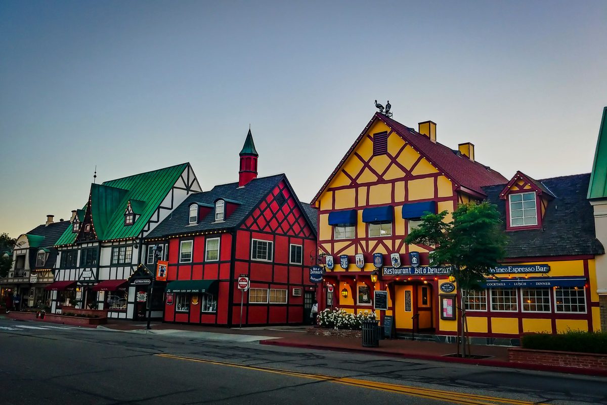 Brightly painted Danish-style storefronts with steep gabled roofs lining a street corner in Solvang, California