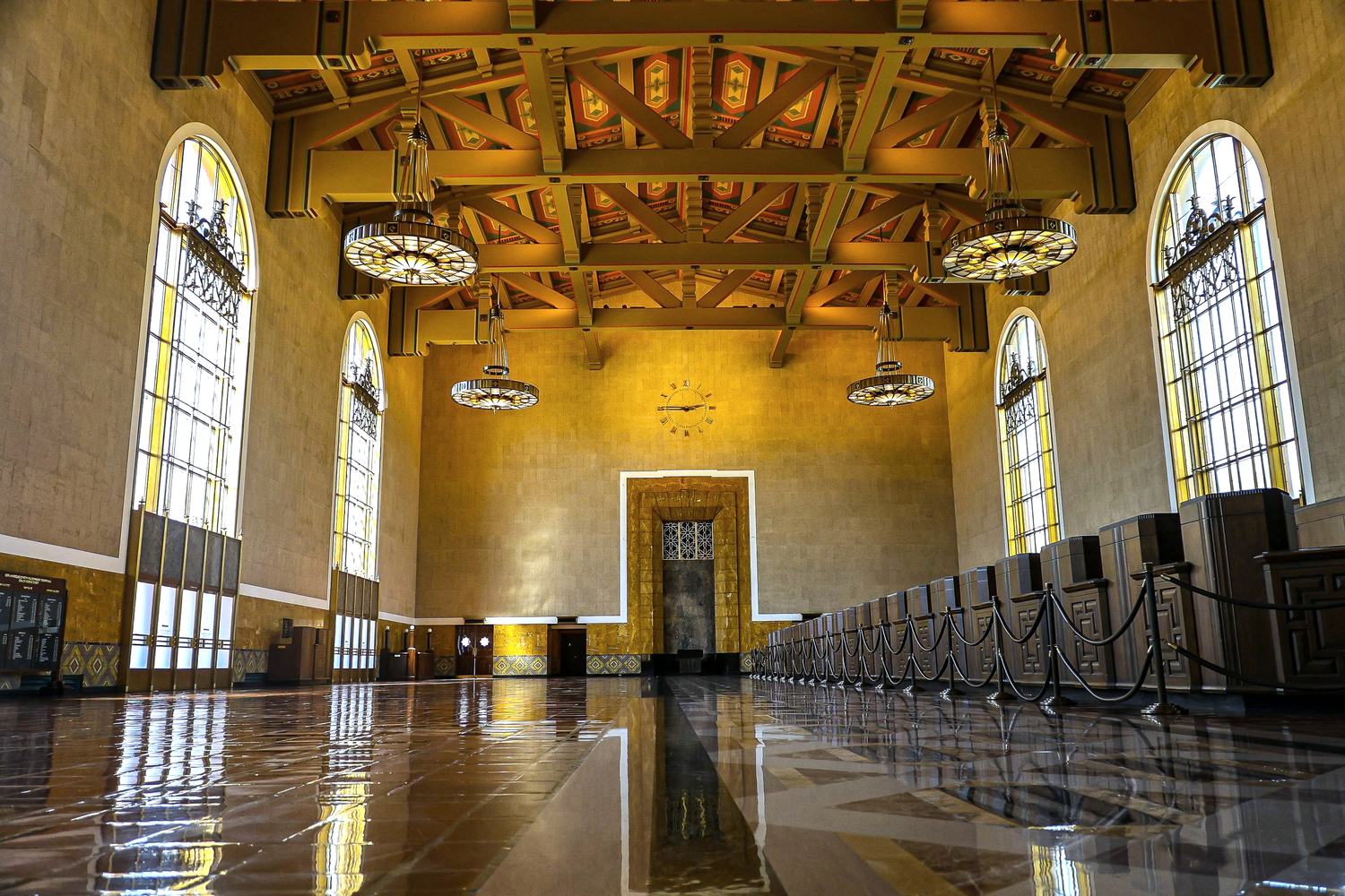 The tiled interior hall of Los Angeles Union Station, its chandeliers hung from a beamed ceiling above tall arched windows