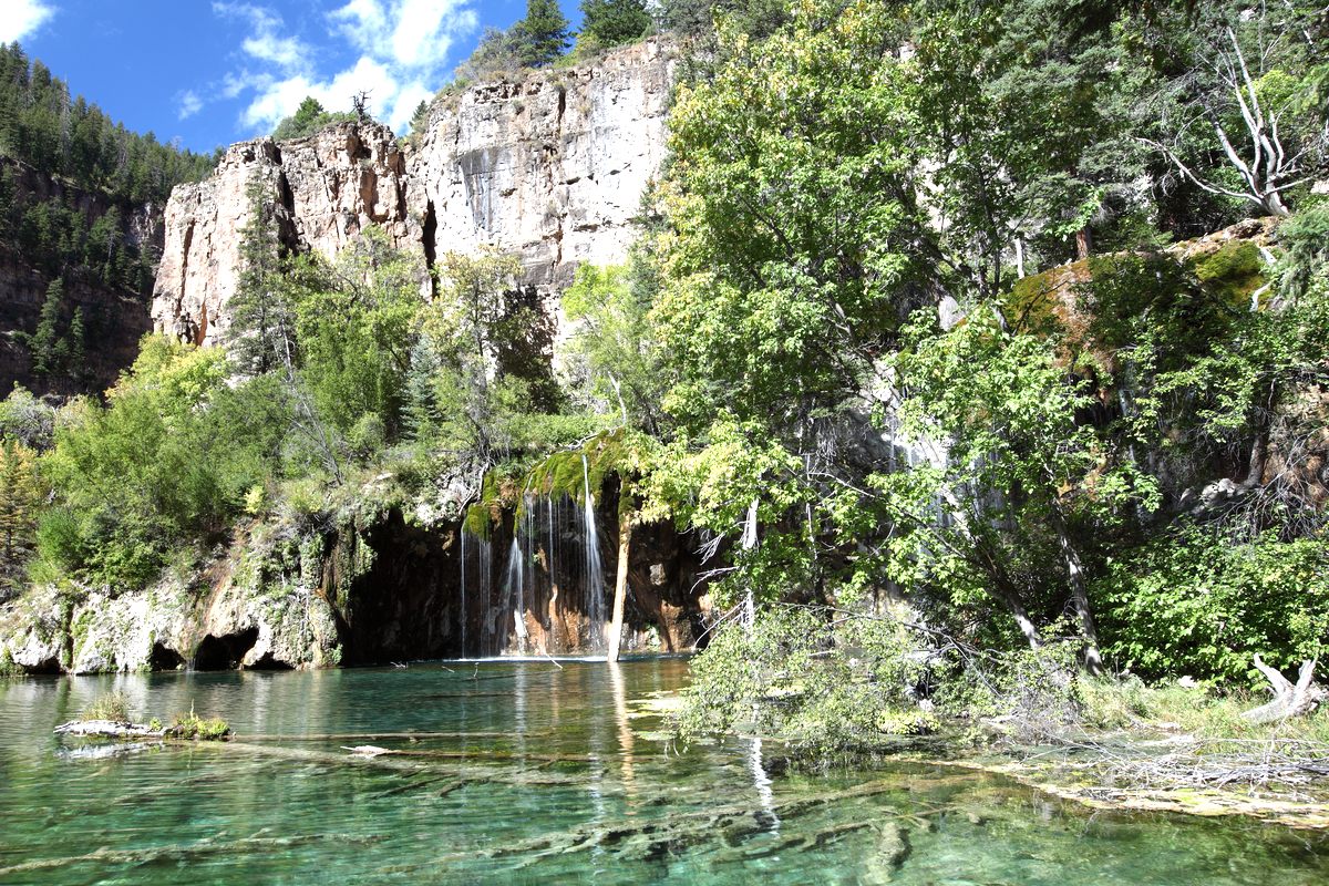 Waterfalls spilling over mossy cliffs into the clear turquoise water of Hanging Lake in Glenwood Canyon, Colorado