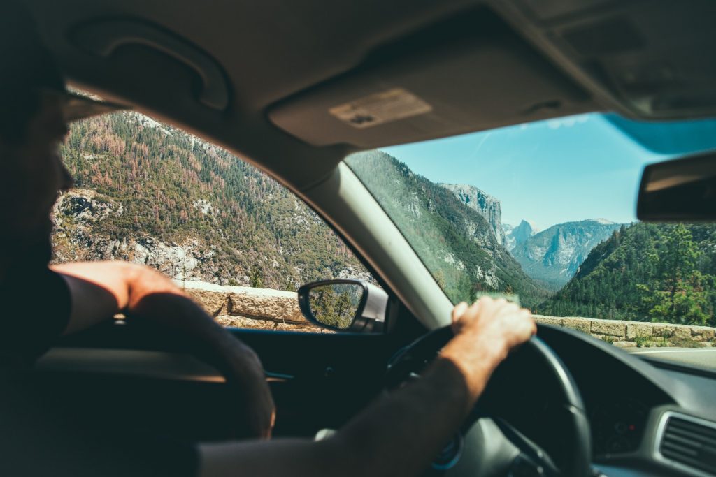 A traveler drives their rental car on a mountain road