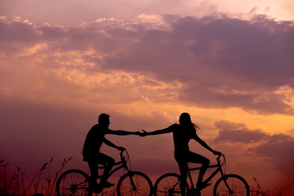 A couple in a long-distance relationship go on a bike ride at sunset.