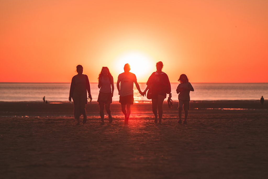 Photo of a family on the beach at sunset.