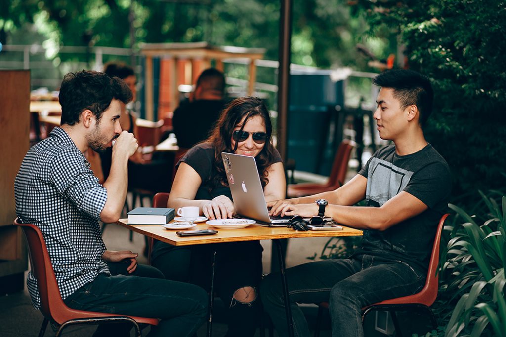 A group of millennials sit around in a coffee shop while on vacation.