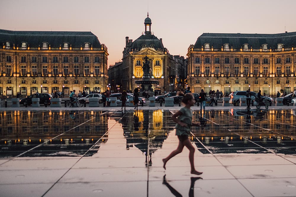 Photo of a girl running through a public square in Bordeaux.